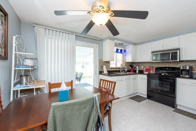 kitchen with sink, backsplash, black electric range oven, white cabinets, and light tile patterned floors