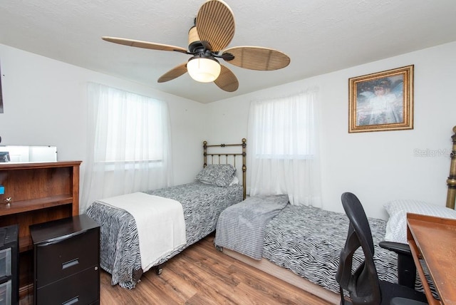 bedroom with ceiling fan, multiple windows, and hardwood / wood-style flooring