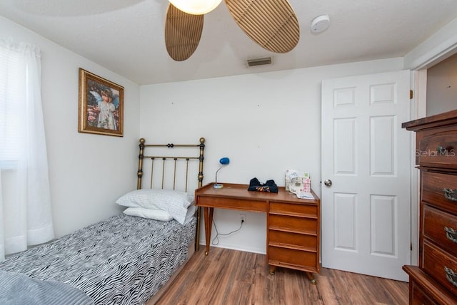 bedroom with built in desk and dark hardwood / wood-style floors