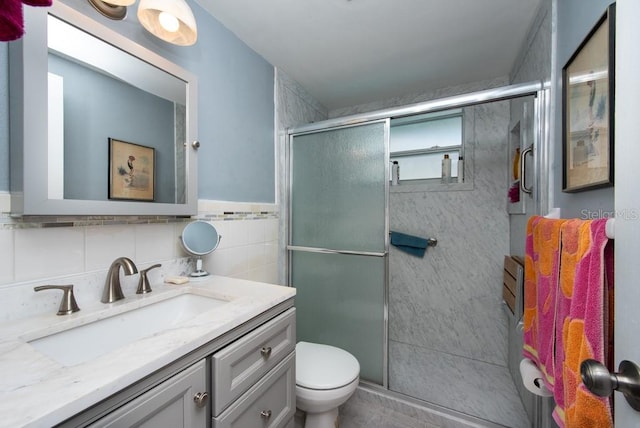 bathroom with vanity, toilet, tile walls, and a shower with door