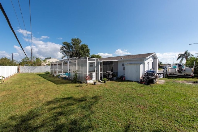 rear view of property with a shed, a lawn, and a lanai