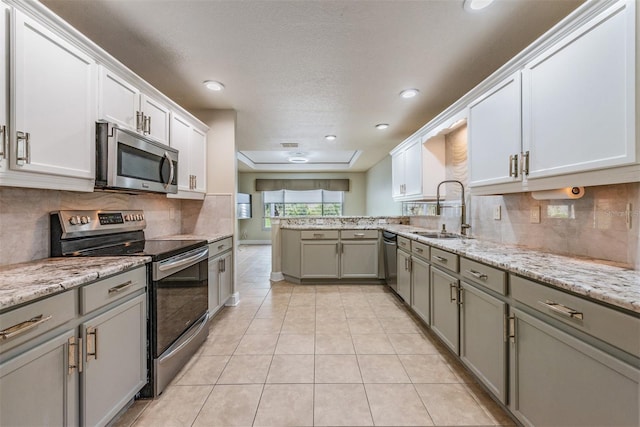 kitchen with sink, light tile patterned flooring, stainless steel appliances, and a textured ceiling