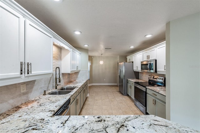 kitchen with tasteful backsplash, light stone countertops, appliances with stainless steel finishes, sink, and white cabinets