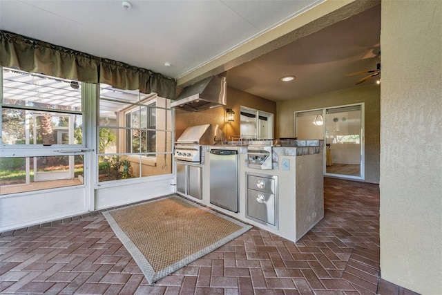 kitchen with kitchen peninsula, ceiling fan, wall chimney range hood, and stainless steel refrigerator