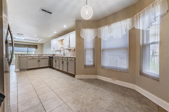 kitchen with appliances with stainless steel finishes, light tile patterned flooring, pendant lighting, a notable chandelier, and sink