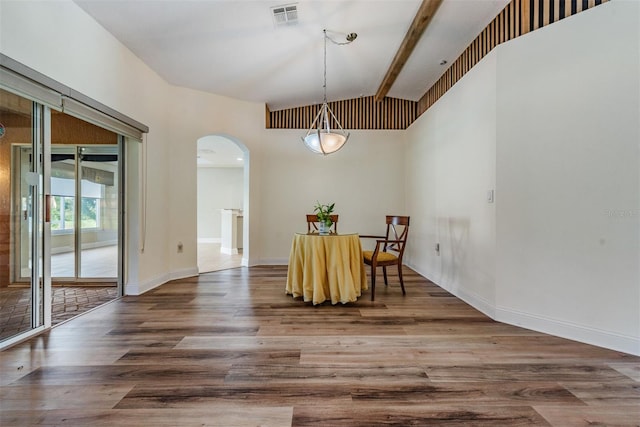 dining area featuring dark wood-type flooring and lofted ceiling with beams