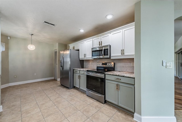 kitchen with appliances with stainless steel finishes, white cabinetry, decorative light fixtures, and backsplash