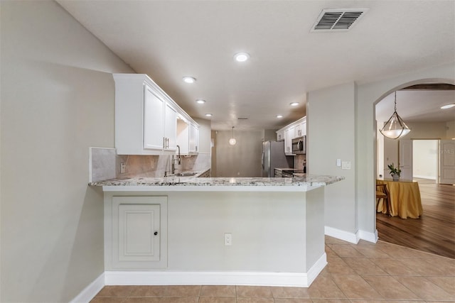 kitchen featuring stainless steel appliances, decorative backsplash, kitchen peninsula, and white cabinets