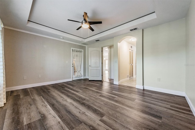 unfurnished room featuring ceiling fan, a tray ceiling, and dark hardwood / wood-style flooring