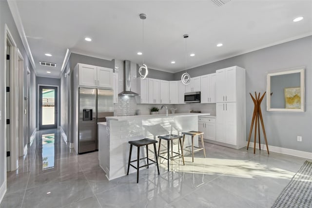 kitchen featuring a kitchen breakfast bar, wall chimney range hood, decorative backsplash, an island with sink, and appliances with stainless steel finishes