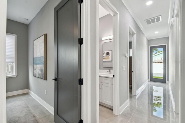 corridor featuring light tile patterned floors and sink