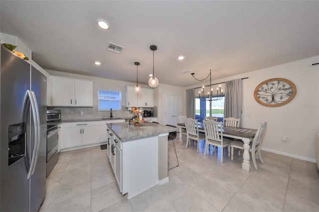 kitchen with tasteful backsplash, white cabinetry, stainless steel appliances, sink, and a center island