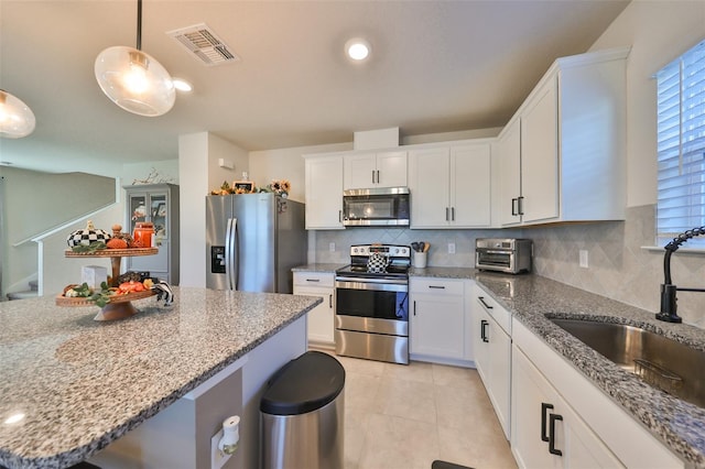 kitchen featuring sink, stainless steel appliances, decorative light fixtures, and white cabinets