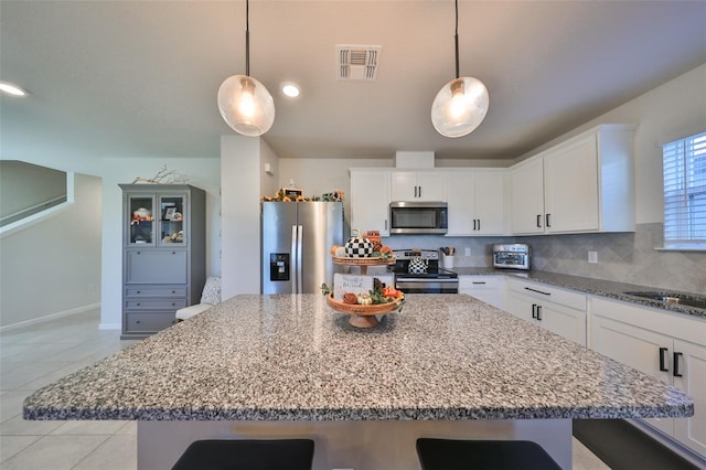 kitchen with appliances with stainless steel finishes, white cabinetry, and pendant lighting