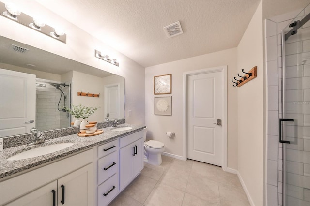 bathroom with tile patterned floors, toilet, a shower with shower door, vanity, and a textured ceiling