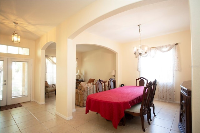 dining space featuring french doors, washer / clothes dryer, an inviting chandelier, and light tile patterned floors