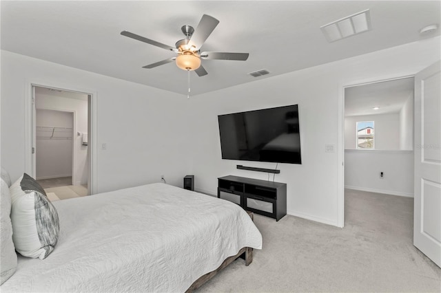 carpeted bedroom with a walk in closet, ceiling fan, and a closet