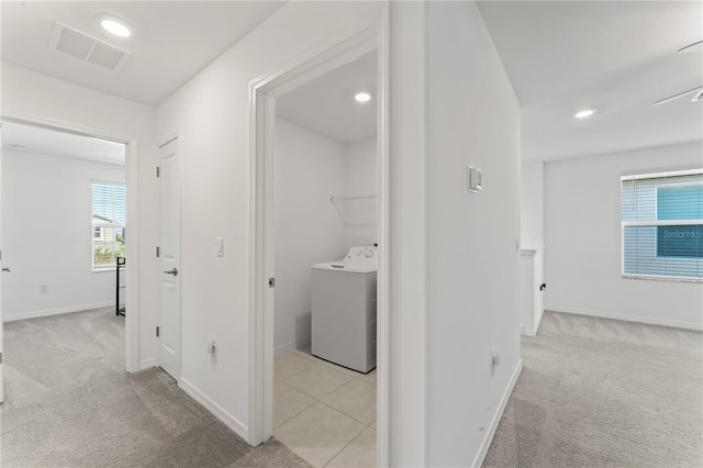 hallway with light carpet and washer / dryer