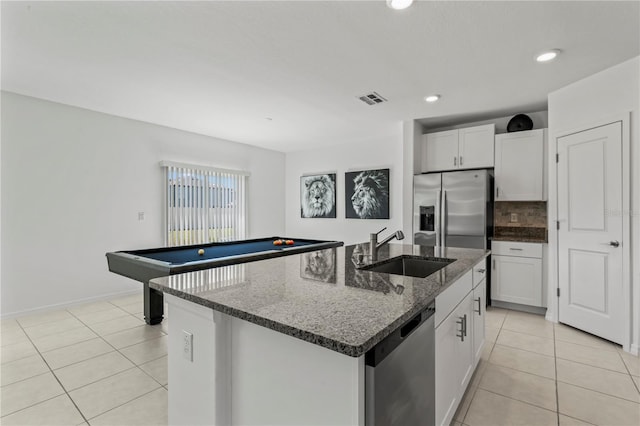 kitchen with appliances with stainless steel finishes, an island with sink, sink, white cabinets, and decorative backsplash