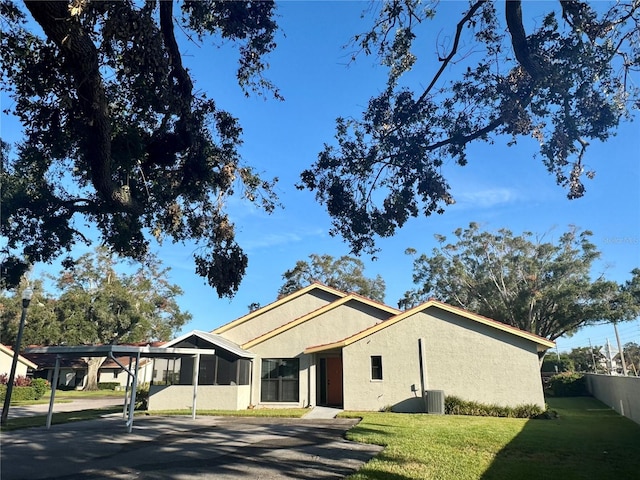 view of side of property with central AC unit, a yard, and a carport