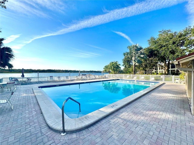 view of pool featuring a water view and a patio area