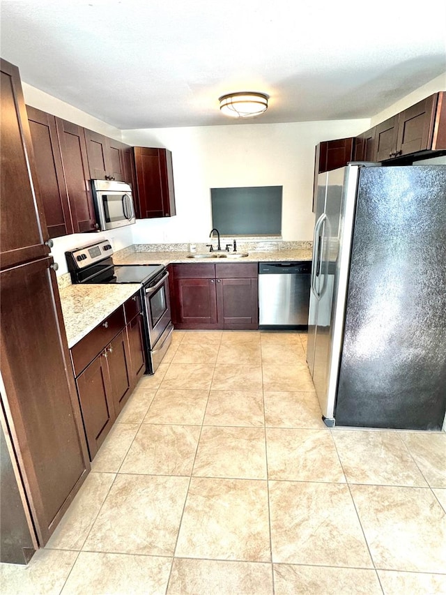 kitchen with dark brown cabinetry, appliances with stainless steel finishes, sink, and light tile patterned floors