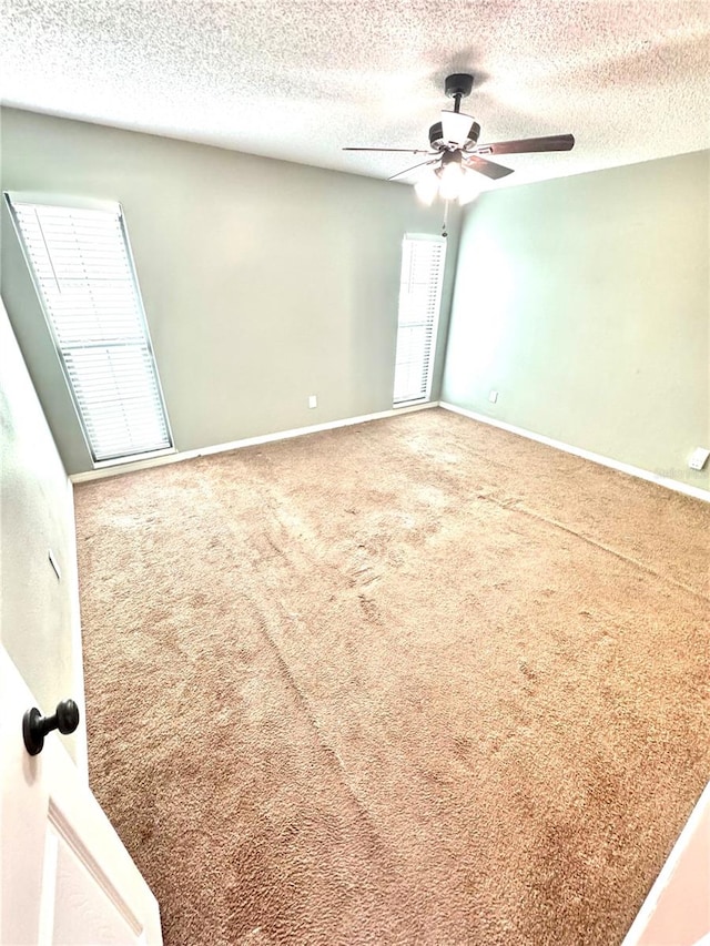 carpeted spare room with a wealth of natural light, a textured ceiling, and ceiling fan