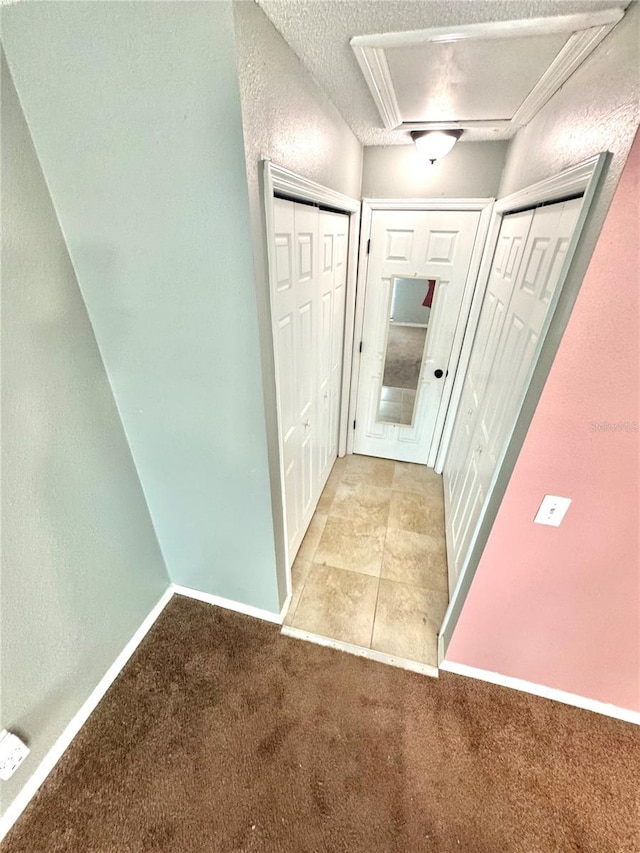 corridor featuring light colored carpet and a textured ceiling