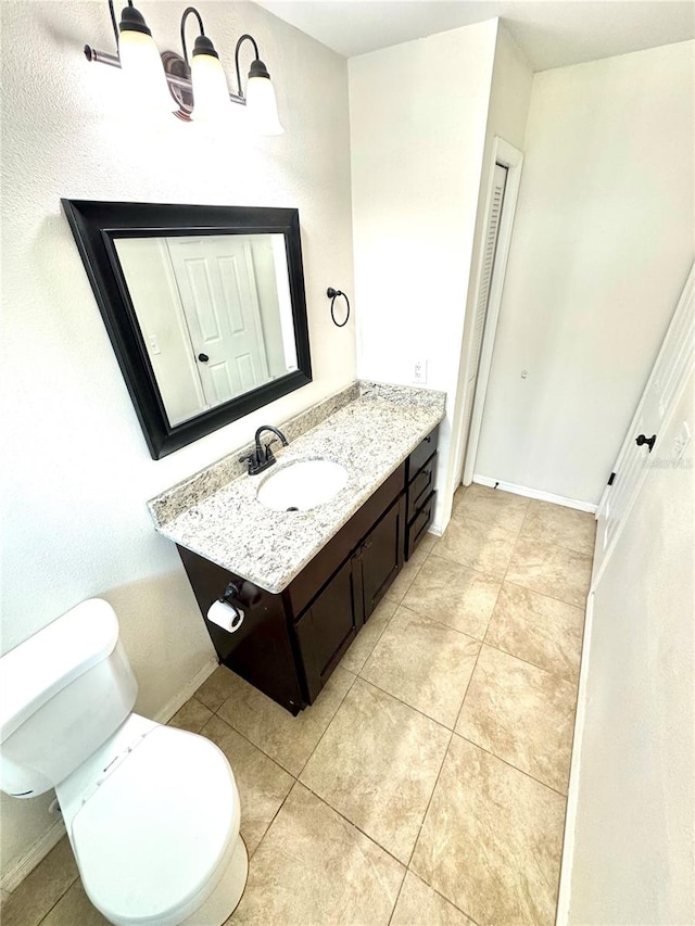 bathroom with toilet, vanity, and tile patterned flooring