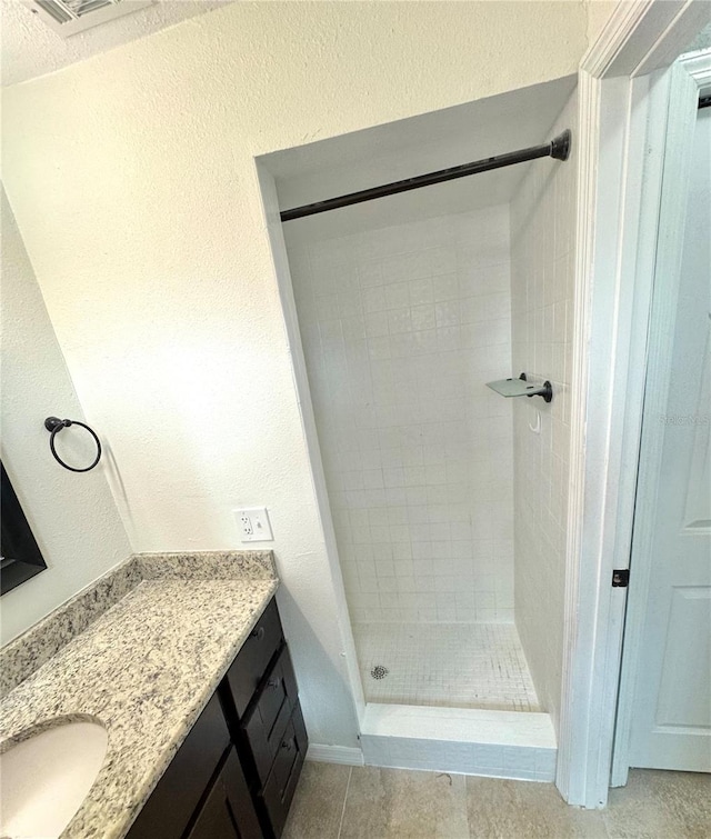 bathroom with vanity, tile patterned floors, and a tile shower