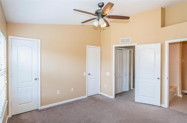 unfurnished bedroom featuring ensuite bath, ceiling fan, high vaulted ceiling, and light colored carpet