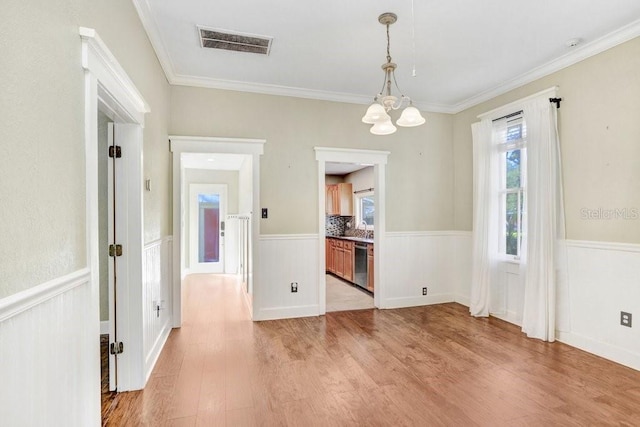 unfurnished dining area with light hardwood / wood-style floors, an inviting chandelier, ornamental molding, and sink