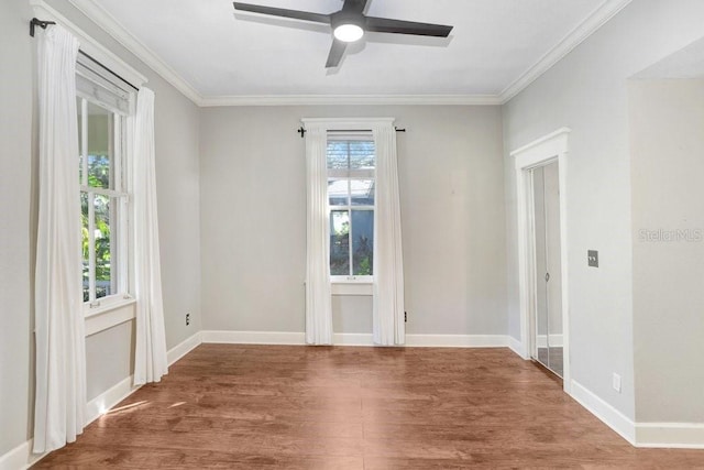 empty room featuring a healthy amount of sunlight, wood-type flooring, and ornamental molding