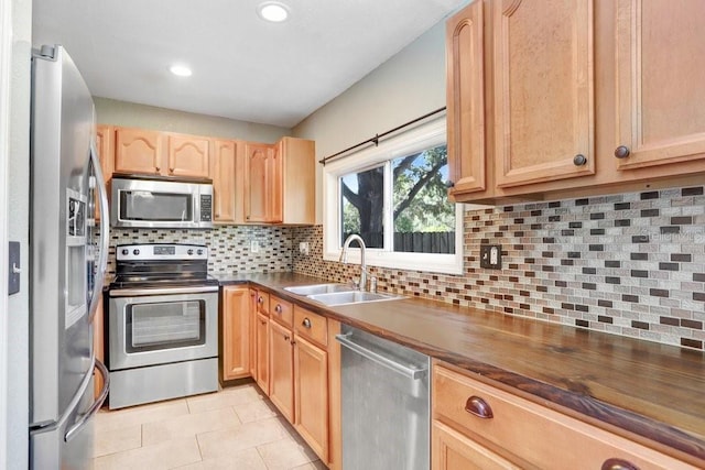 kitchen with tasteful backsplash, light tile patterned floors, appliances with stainless steel finishes, light brown cabinetry, and sink