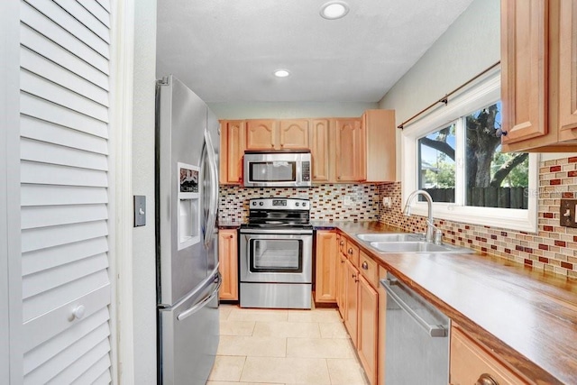 kitchen featuring decorative backsplash, stainless steel appliances, sink, light tile patterned flooring, and light brown cabinetry