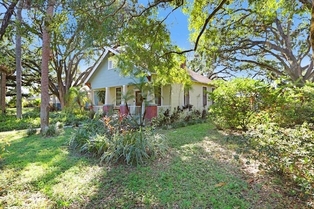 view of side of home with covered porch and a lawn