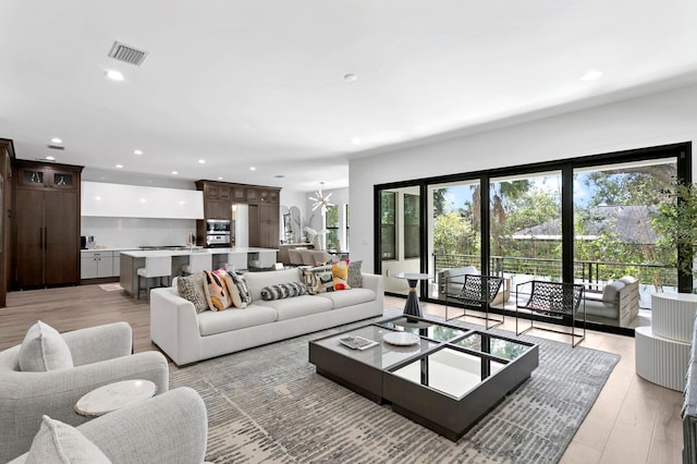 living room with light hardwood / wood-style floors and a notable chandelier