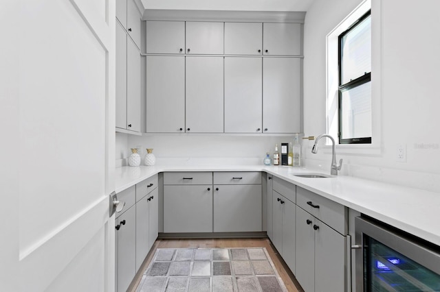 kitchen featuring gray cabinetry, wine cooler, sink, and light hardwood / wood-style floors