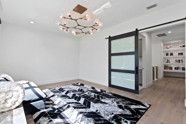 bedroom featuring hardwood / wood-style floors, a barn door, and a chandelier