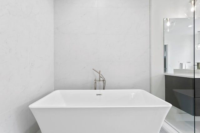 bathroom featuring tile walls, vanity, and a bath