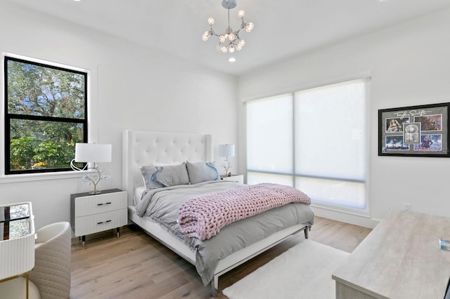 bedroom featuring an inviting chandelier, multiple windows, and light wood-type flooring