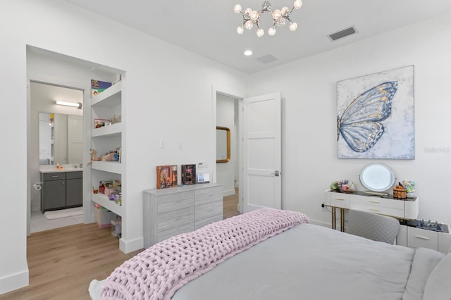 bedroom with light hardwood / wood-style floors, ensuite bath, and a chandelier