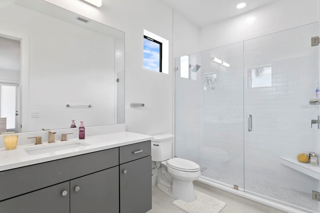 bathroom with toilet, vanity, and a shower with door