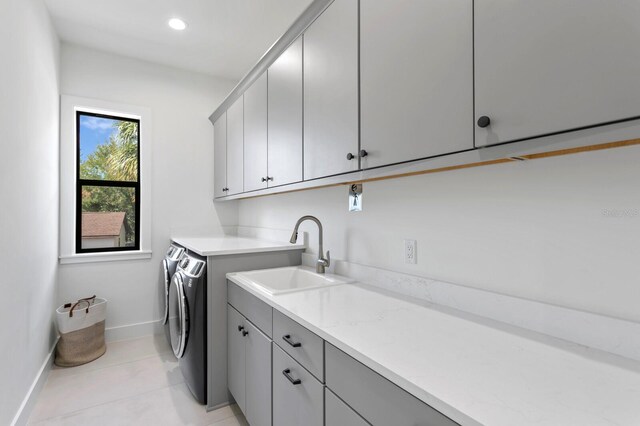 clothes washing area featuring cabinets, sink, separate washer and dryer, and light tile patterned floors