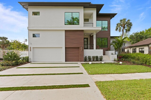 contemporary house featuring a balcony, a garage, and a front lawn