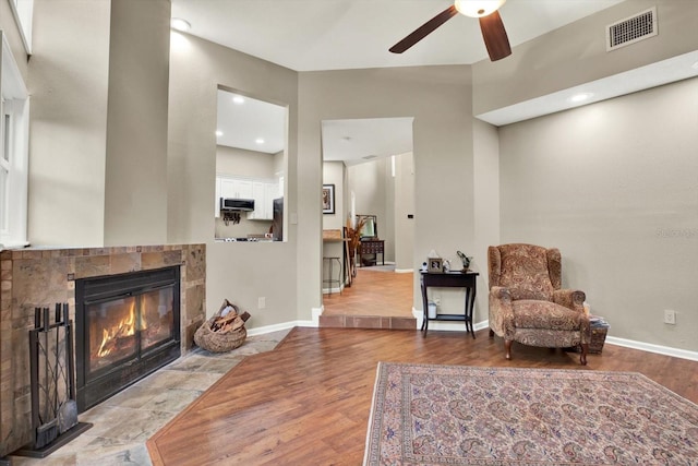 sitting room with ceiling fan, light hardwood / wood-style flooring, and a tile fireplace