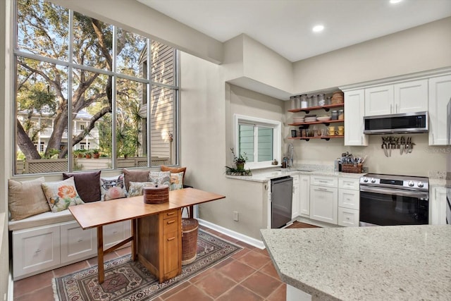 kitchen featuring dark tile patterned flooring, light stone counters, appliances with stainless steel finishes, and white cabinets