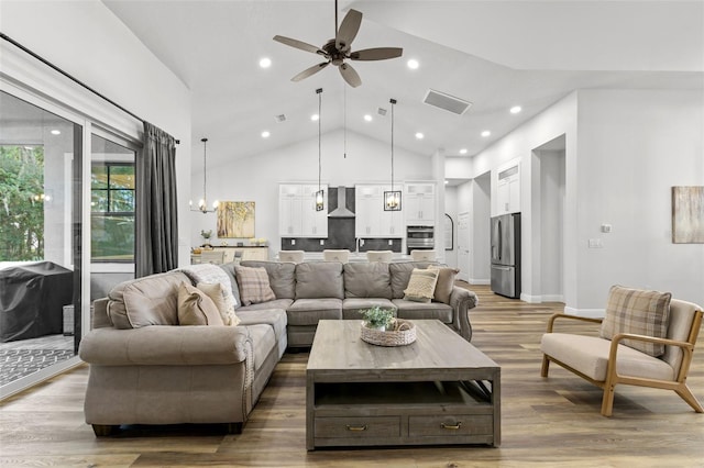 living room with ceiling fan, wood-type flooring, and high vaulted ceiling