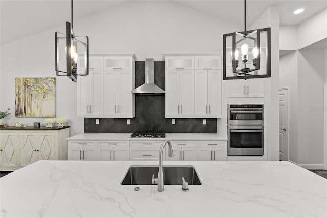 kitchen with pendant lighting, sink, stainless steel double oven, and wall chimney exhaust hood