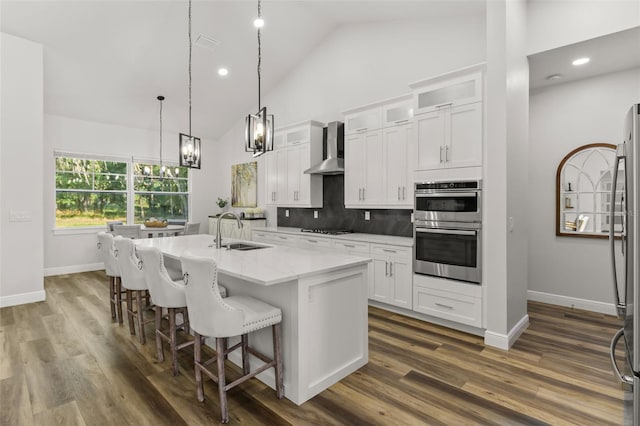 kitchen featuring a center island with sink, white cabinets, sink, decorative backsplash, and wall chimney exhaust hood